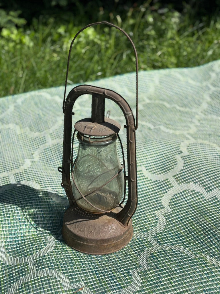 Vintage-style lantern on a textured surface with grass in the background
