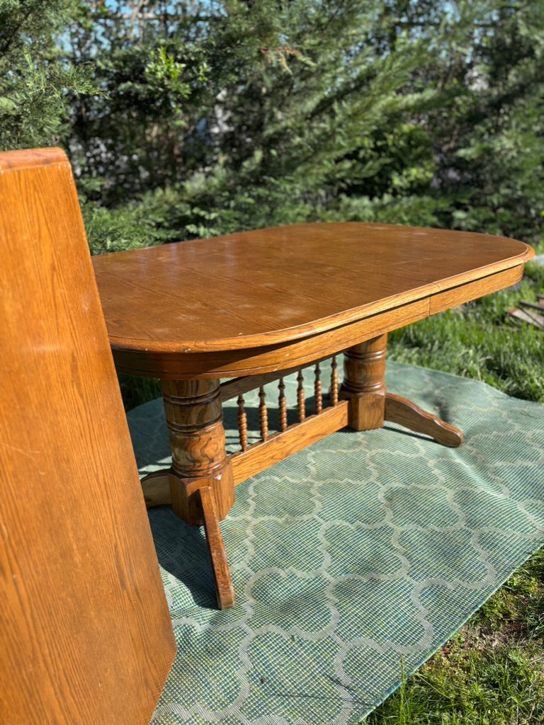 Wooden dining table with a bench on a green mat outdoors