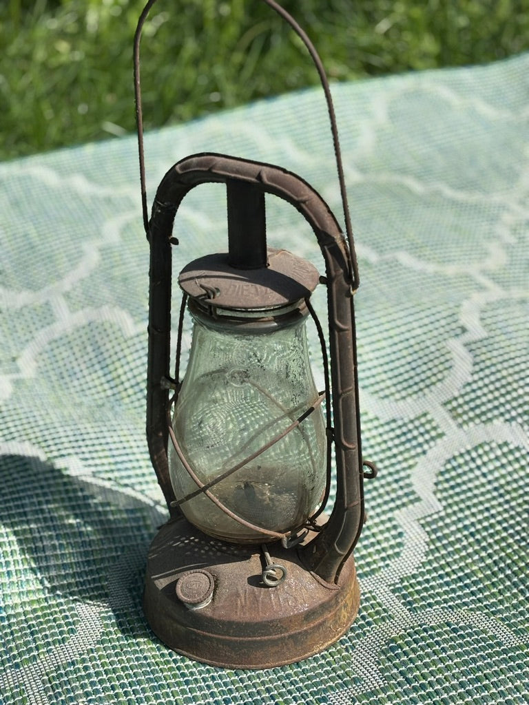 Vintage-style lantern on a textured green surface with grass in the background