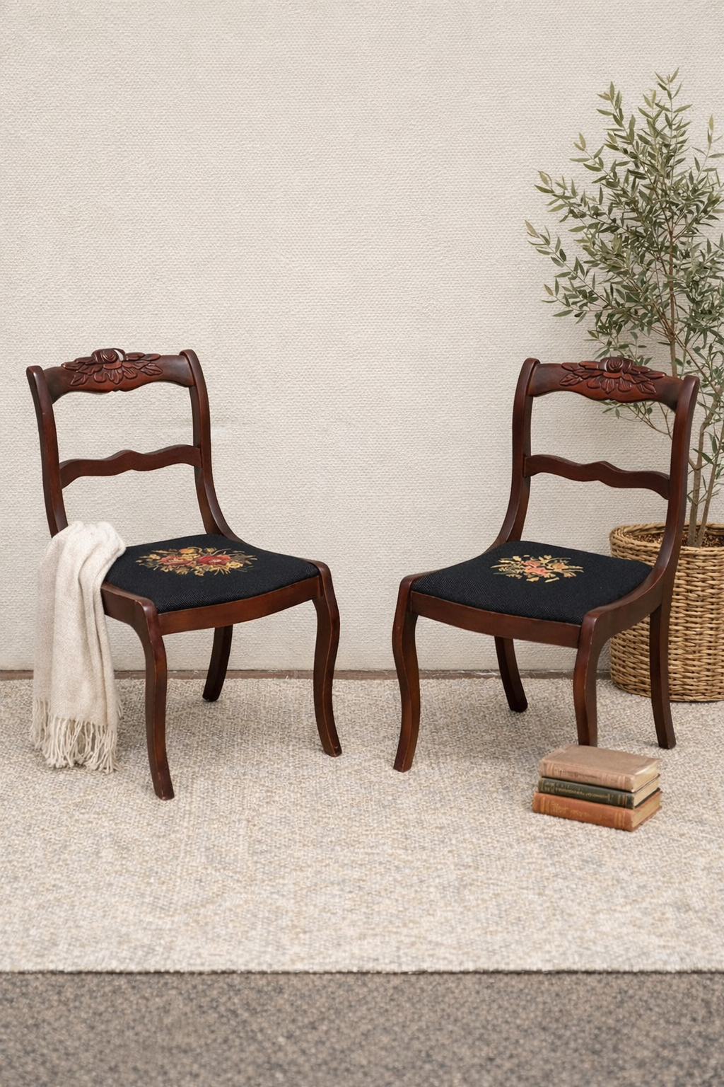 Two wooden chairs with embroidered cushions on a neutral background