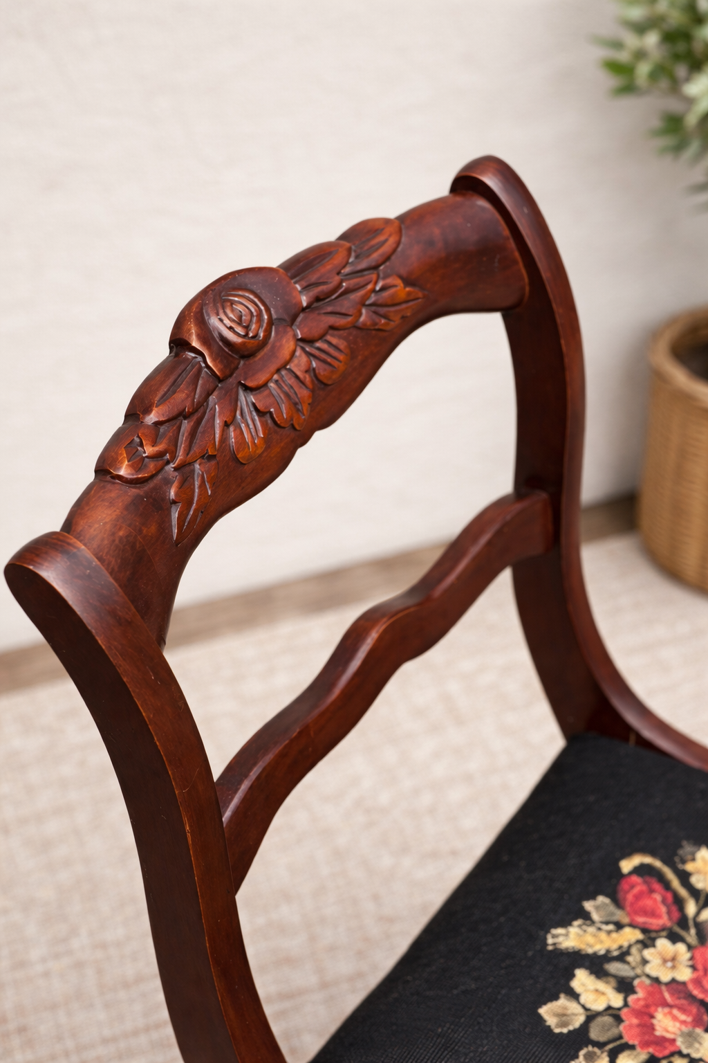 Close-up of a wooden chair with floral carvings on the backrest.