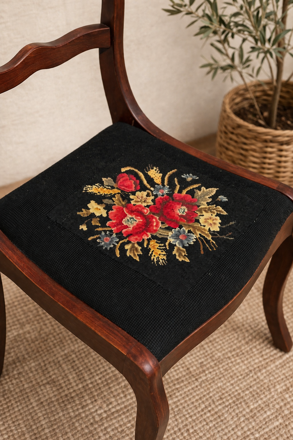 Chair with black embroidered floral cushion next to a plant