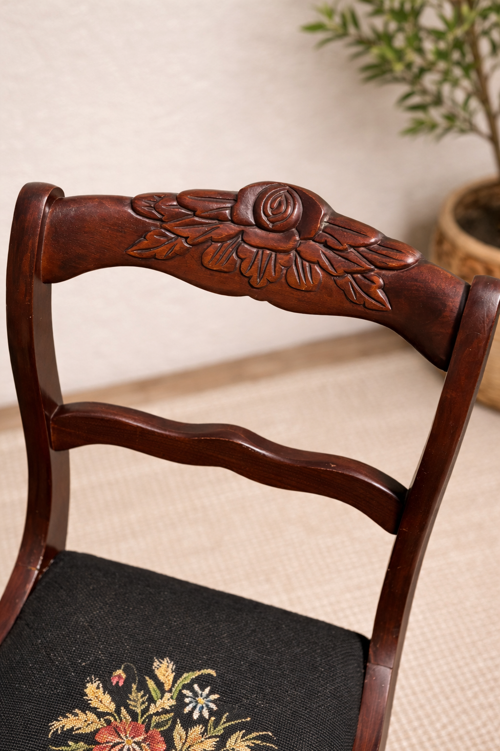 Wooden chair with floral carvings on the backrest and seat, against a neutral background.