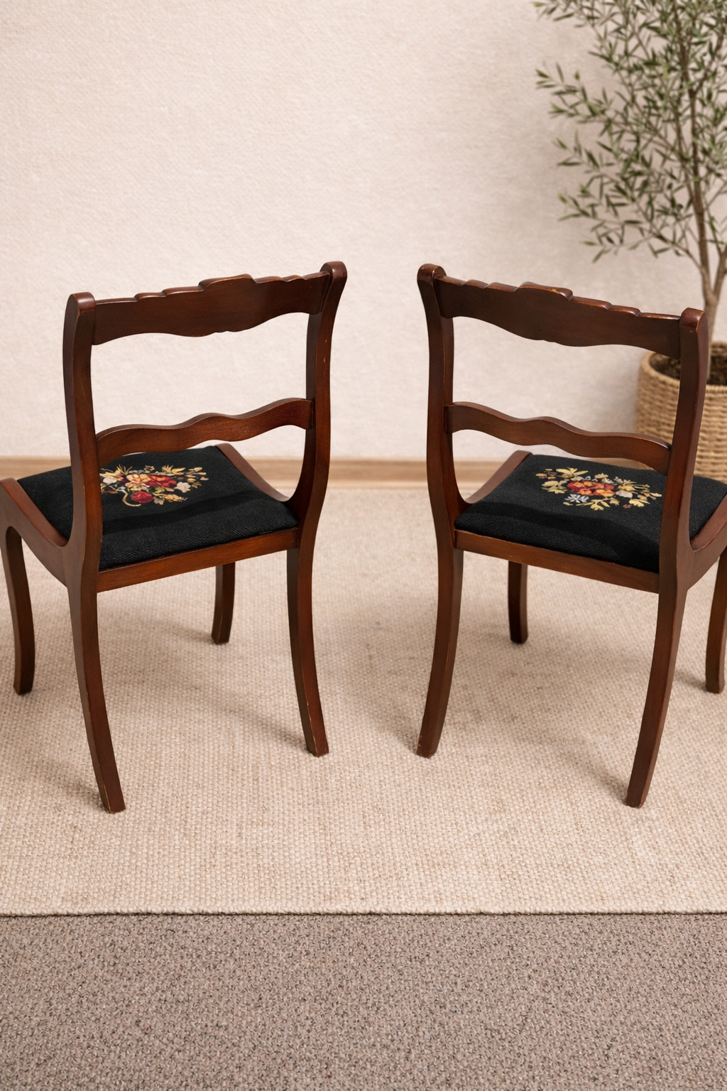 Two wooden chairs with floral cushions on a beige carpet