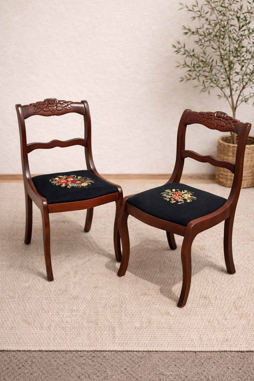 Two wooden chairs with embroidered cushions on a carpeted floor.