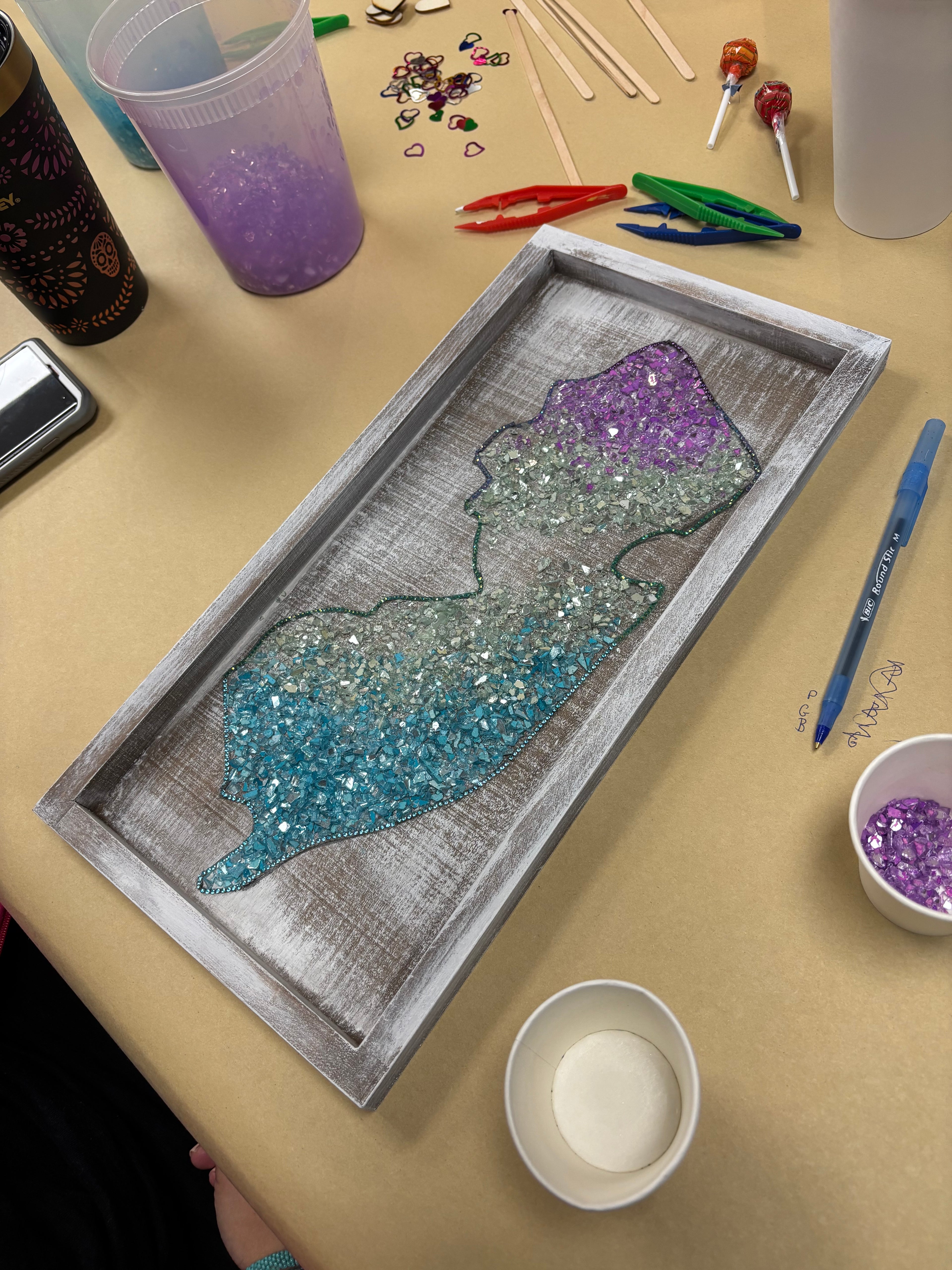 Decorative tray with glittery New Jersey design on a table with craft supplies