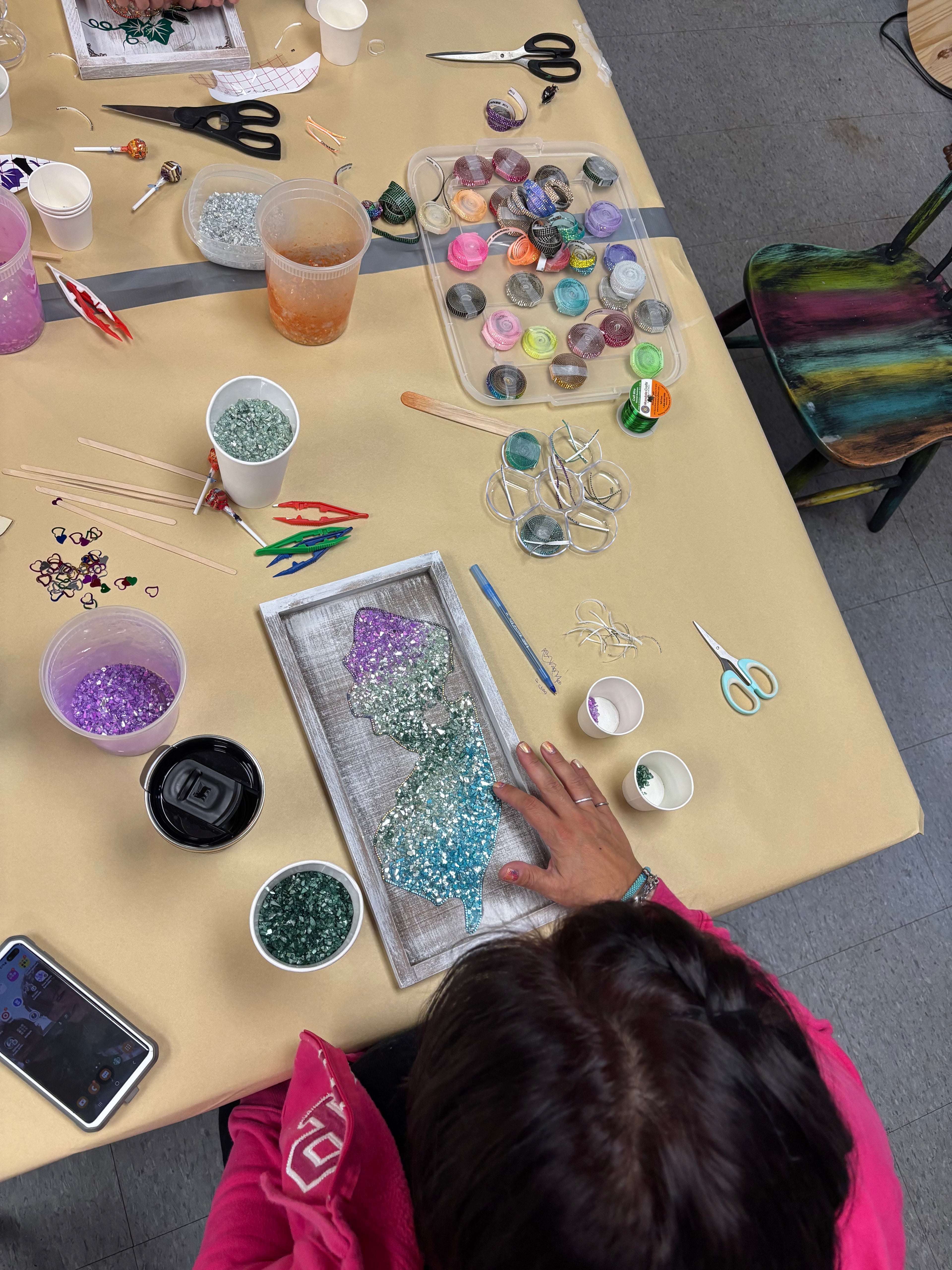 Person working on a craft project with various materials on a table