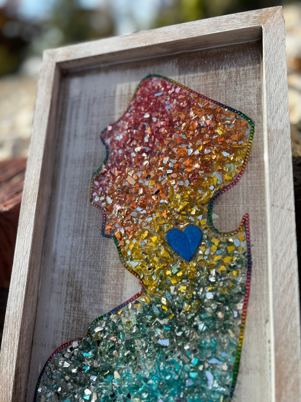 Colorful silhouette art piece with a blue heart in a wooden frame.