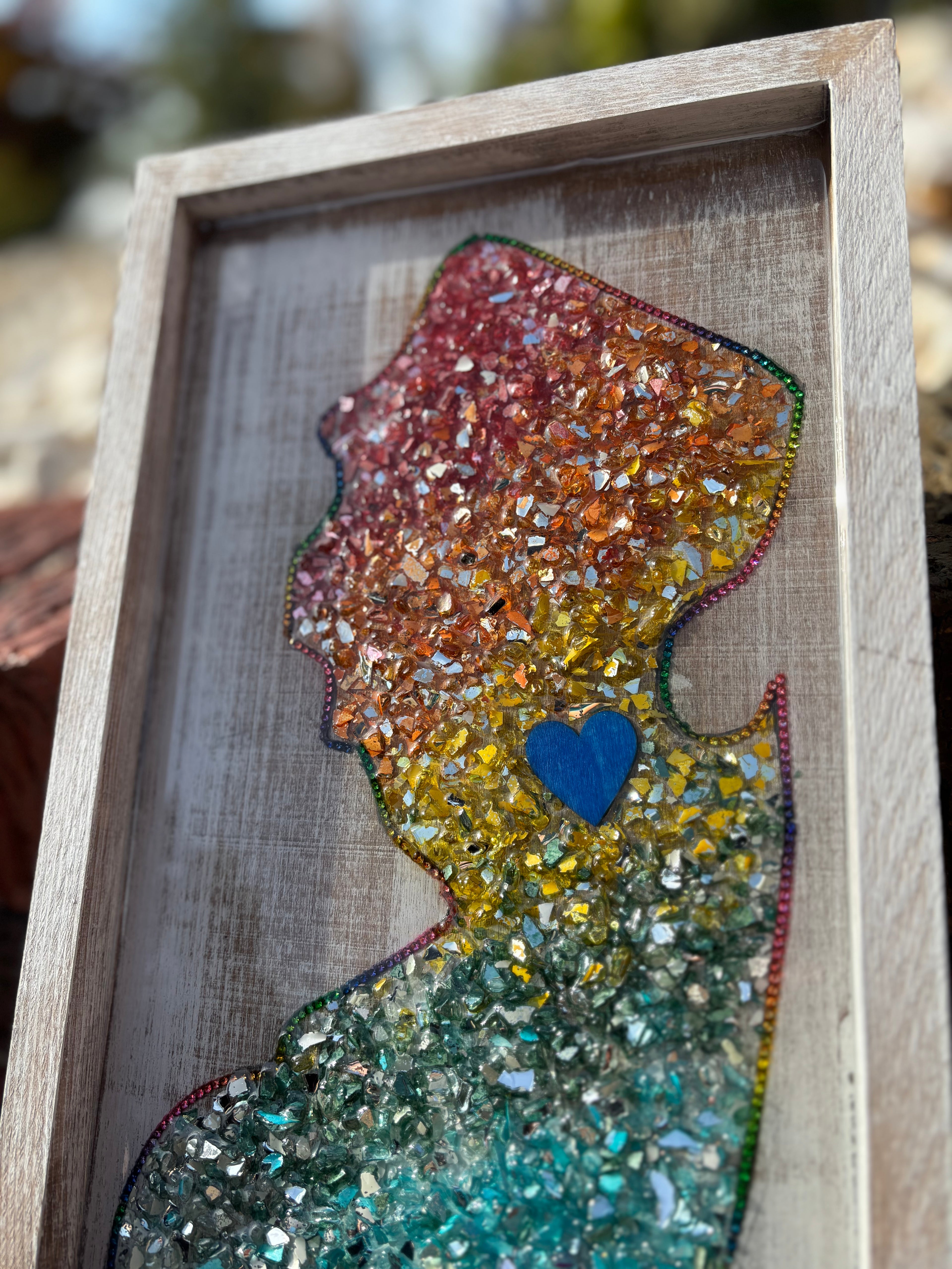 Colorful silhouette art piece with a blue heart in a wooden frame.